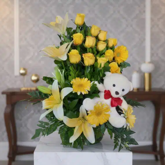 Arreglo Floral Exótico Amaretto con Rosas Amarillas y Lirios Arreglo floral exótico Amaretto con rosas amarillas, lirios blancos y gerberas, acompañado de un oso de peluche blanco con la