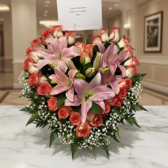 Arreglo Floral Feliz Contigo: Lirios y Rosas en Entorno Premium Arreglo floral Feliz Contigo con lirios rosados y rosas bicolor sobre mesa de mármol, fondo elegante de lobby de hotel boutiq