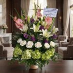 Arreglo fúnebre Te Fuiste con lirios blancos, gladiolos rosas, rosas blancas y hortensias verdes, en sala de velación premium