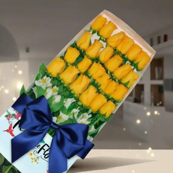 Caja de 24 Rosas Amarillas: Regalo Elegante y Vibrante para Toda Ocasion Caja de 24 rosas amarillas frescas y vibrantes, dispuestas elegantemente con follaje blanco, atadas con un lazo azul oscuro,