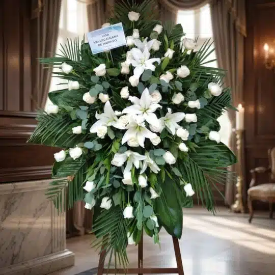 Pedestal fúnebre 'Eternidad' con rosas blancas, lirios y follaje verde, en una elegante sala de velación con luz natural suav